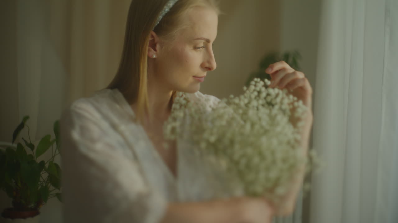 Pensive Woman Touching Gypsophila Bouquet by Window