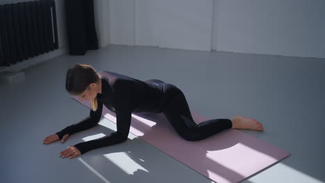 mujer haciendo yoga estirándose en una alfombra rosa