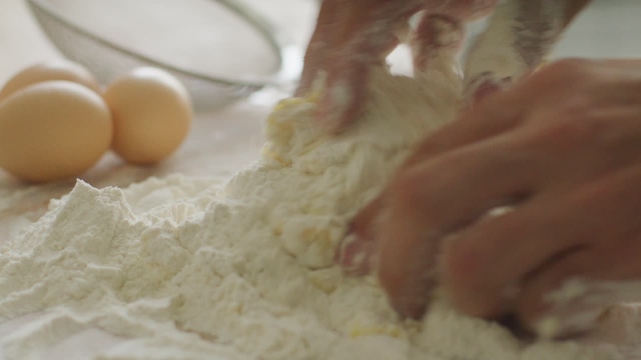 Hands Kneading Mixture of Flour and Eggs on Kitchen Table