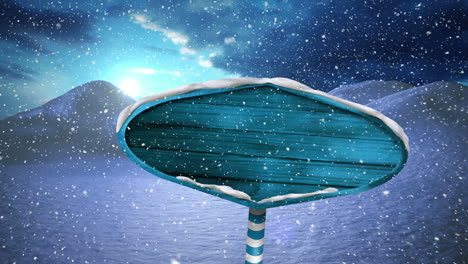 snow falling over blue wooden sign post on winter landscape against clouds in the sky