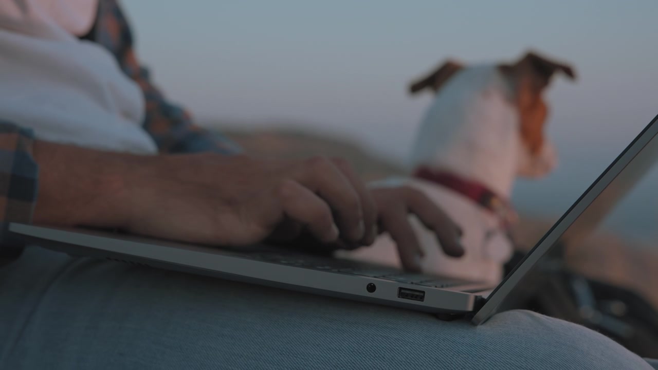 Un uomo che lavora al portatile accanto a un cane