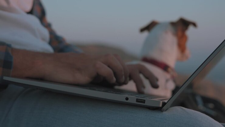 A man working on laptop next to a dog