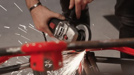 grinding metal from vehicle frame inside workshop by male mechanic