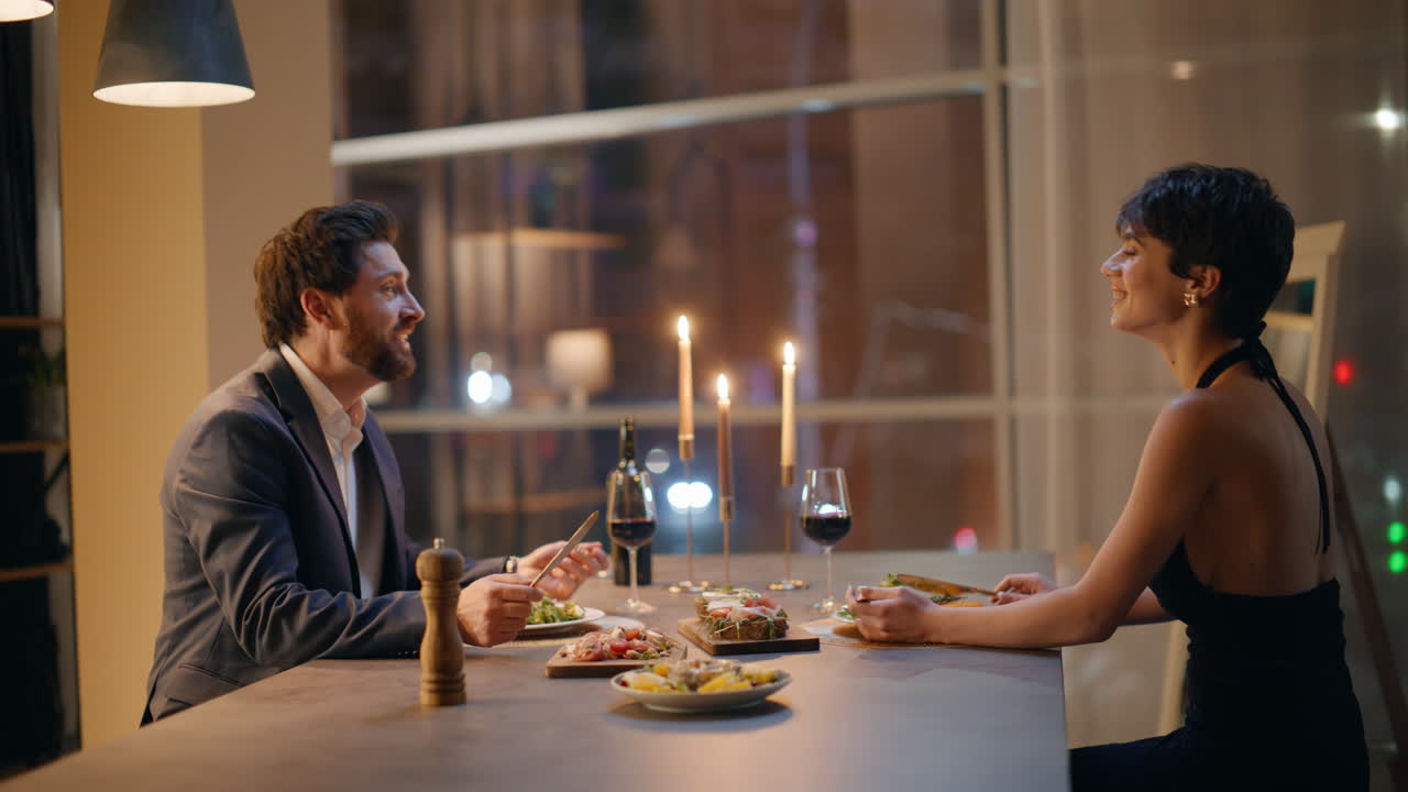 Coppia felice che conversa durante una cena romantica in un appartamento di sera. Una coppia innamorata la sera.