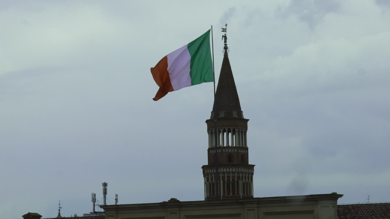 Grande bandiera italiana in una giornata nuvolosa e coperta, con una chiesa sullo sfondo a Milano