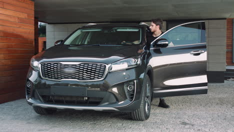 casual man going out luxury car at home. closeup of serious driver locking auto