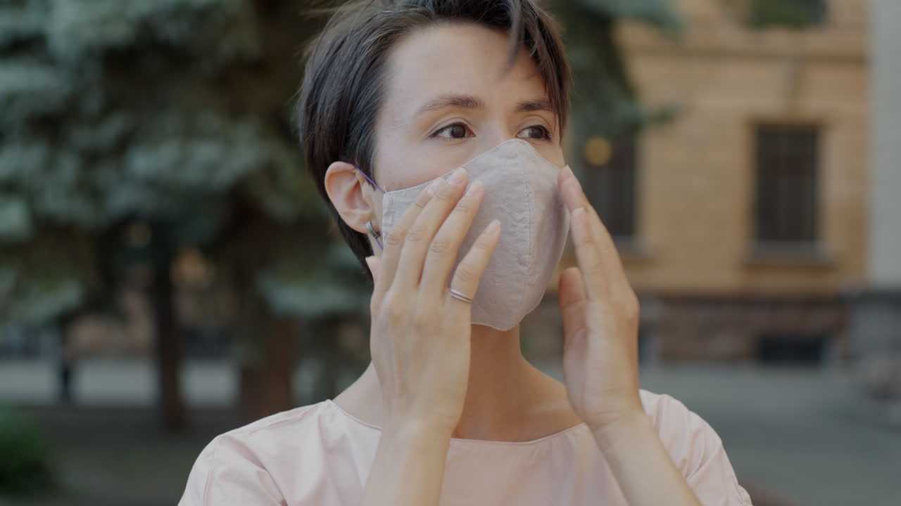 야외에서 얼굴 마스크를 조정하는 여성