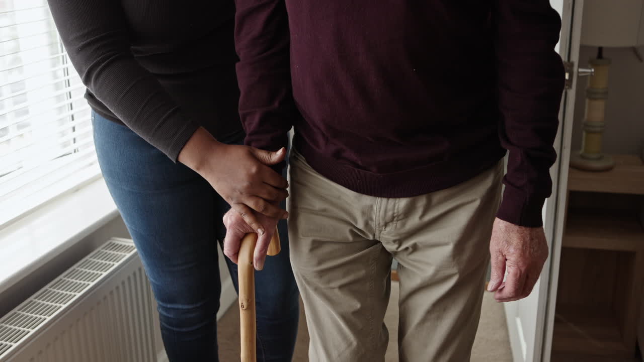 Elderly person receiving assistance with a walking stick