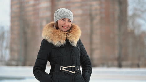 woman in winter clothes wearing a wool cap and looking at camera outdoor