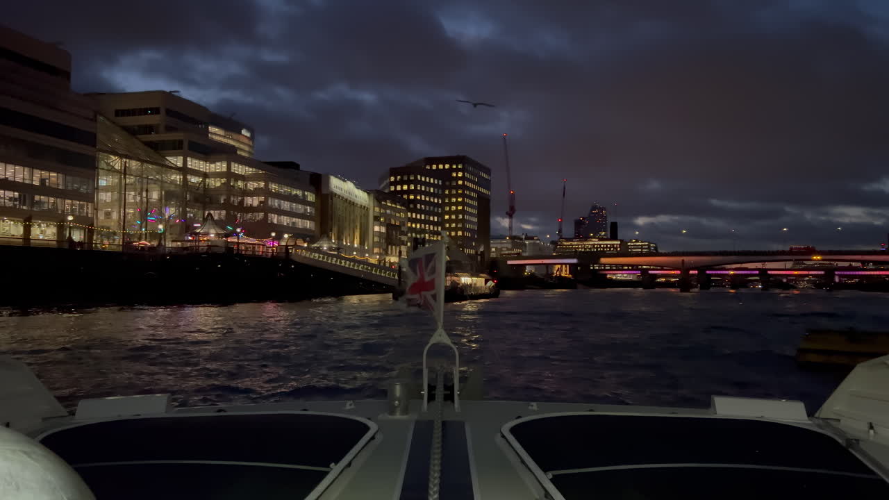 The flag of the United Kingdom waving on a boat moving on the Thames River in the evening in London, England