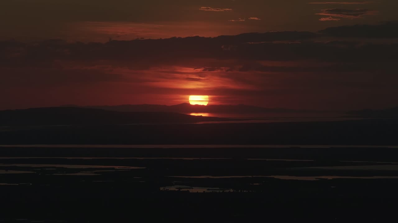 Drohnenansicht vom Bountiful Canyon in Utah auf einen goldenen Sommer-Sonnenuntergang über dem Salt Lake Valley mit Wolken, Bergen und Wasserteichen, die das Licht des Great Salt Lake reflektieren