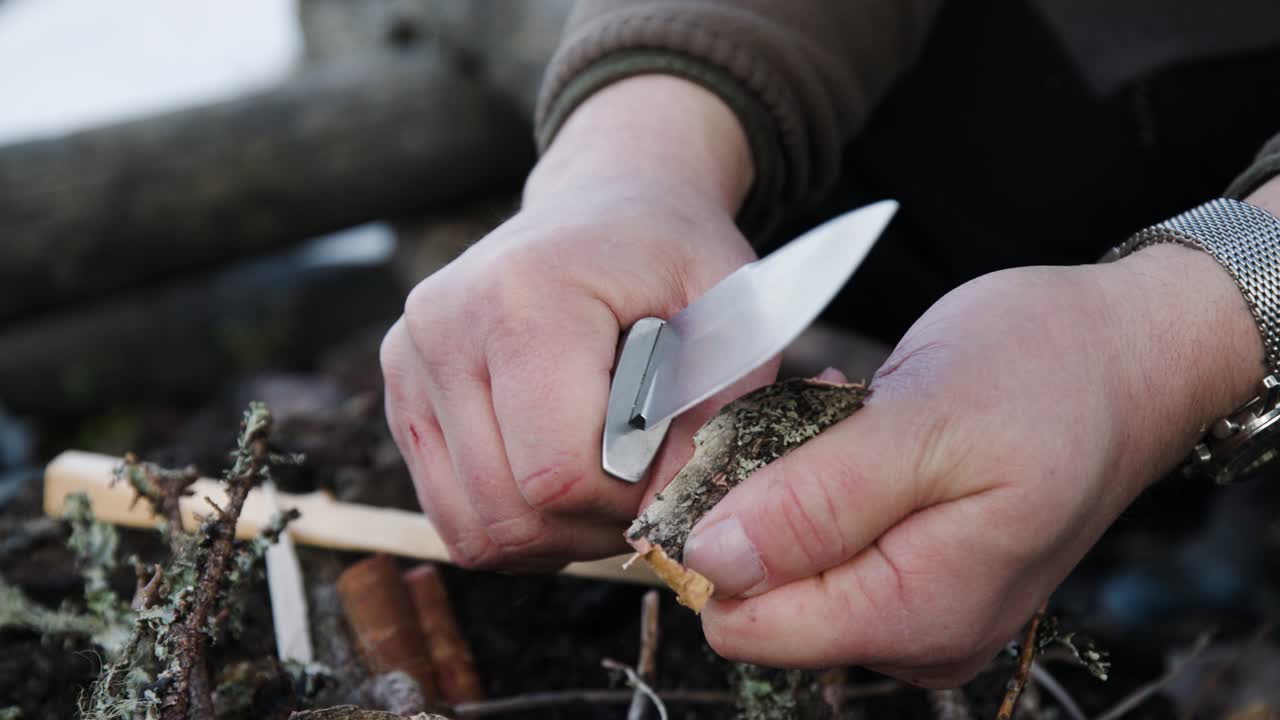 Man carving pieces of birchwood with knife