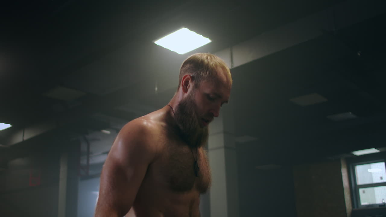 atleta masculino cansado en el gimnasio descansa y se prepara para realizar un ejercicio. atleta sudoroso en cámara lenta respira fuertemente y se concentra en el ejercicio