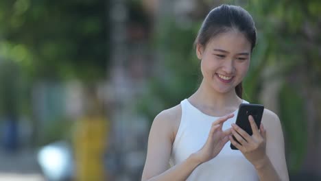 young happy beautiful asian businesswoman using phone outdoors