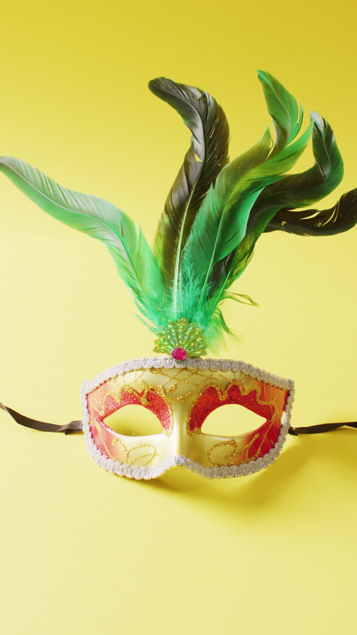Video verticale di maschera di carnevale con piume verdi su sfondo giallo con spazio per il testo.