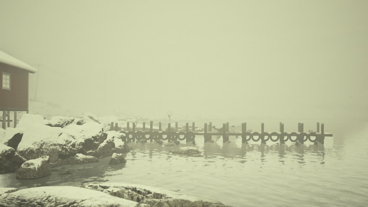 Snowy dock by a quiet lake in a foggy winter landscape