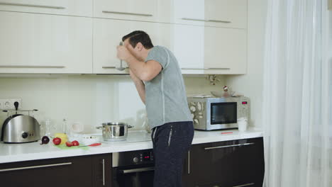 hombre feliz cocinando una cena saludable en casa. marido alegre hablando por teléfono