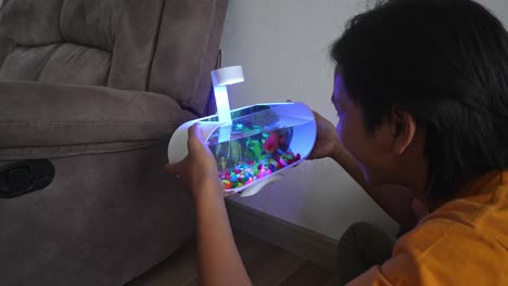 young asian man talking with his goldfish in the aquarium