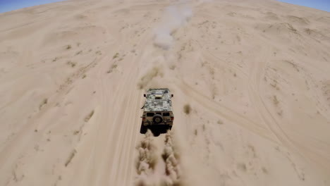 military vehicle driving through sand dunes
