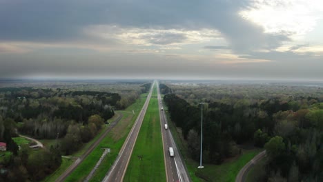 american highway with green forest and majestic cloudy sky in aerial