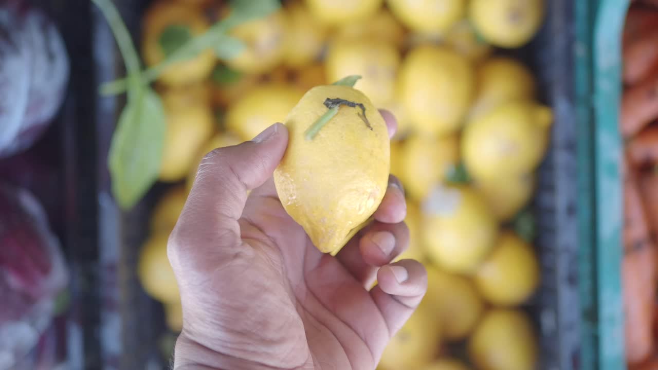 Hand holding a lemon in a grocery store