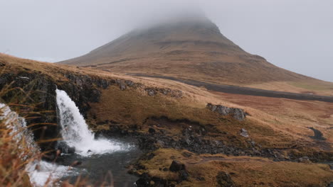 Base-De-La-Cascada-De-Kirkjufellsfoss,-Kirkjufell-Cubierta-De-Niebla-En-El-Fondo