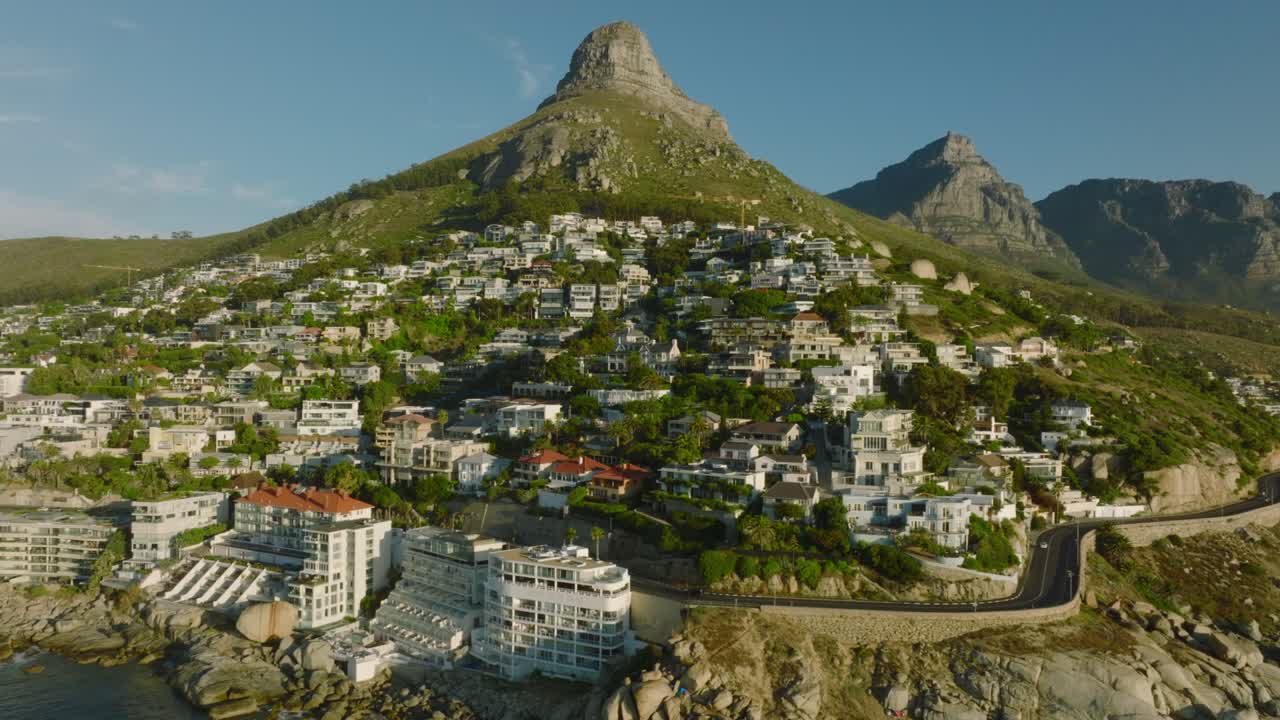 해변 의 가파른 경사 에 있는 고급스러운 아파트 들 의 슬라이드 와 팬  ⁇ . 배경 에 있는 산 들. 케이프 타운, 남아프리카 공화국