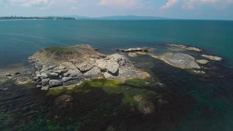 Aerial-panning-shot-of-big-cliffs-in-the-sea-with-vegetation-and-birds-1