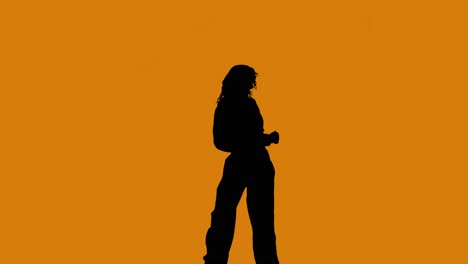 Studio-Silhouette-Einer-Frau,-Die-Vor-Orangefarbenem-Hintergrund-Tanzt