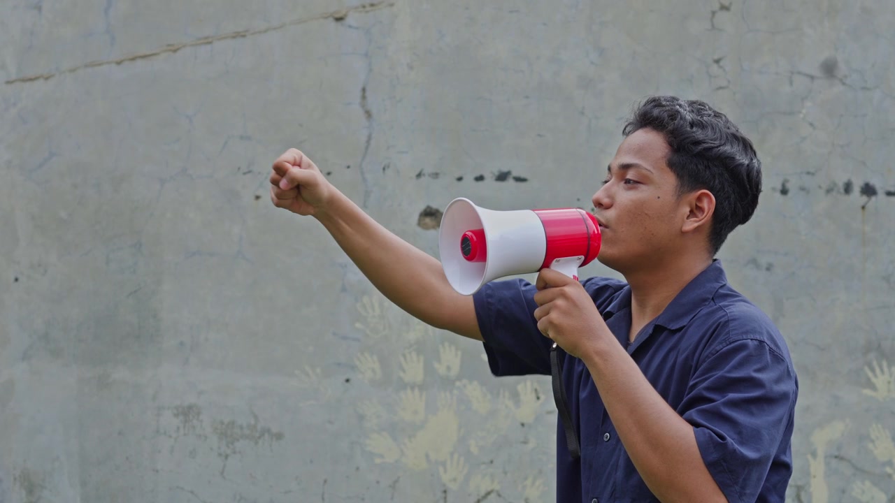 Young activist using bullhorn to lead protest gesturing with hand for press freedom concept