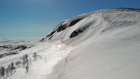winter mountainscape with frozen snowdrift overhanging cliff, tracking in on snowdrift