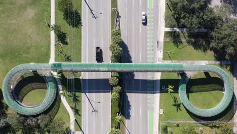 an aerial view directly over a pedestrian walkway which crosses a six lane highway on a sunny day in florida