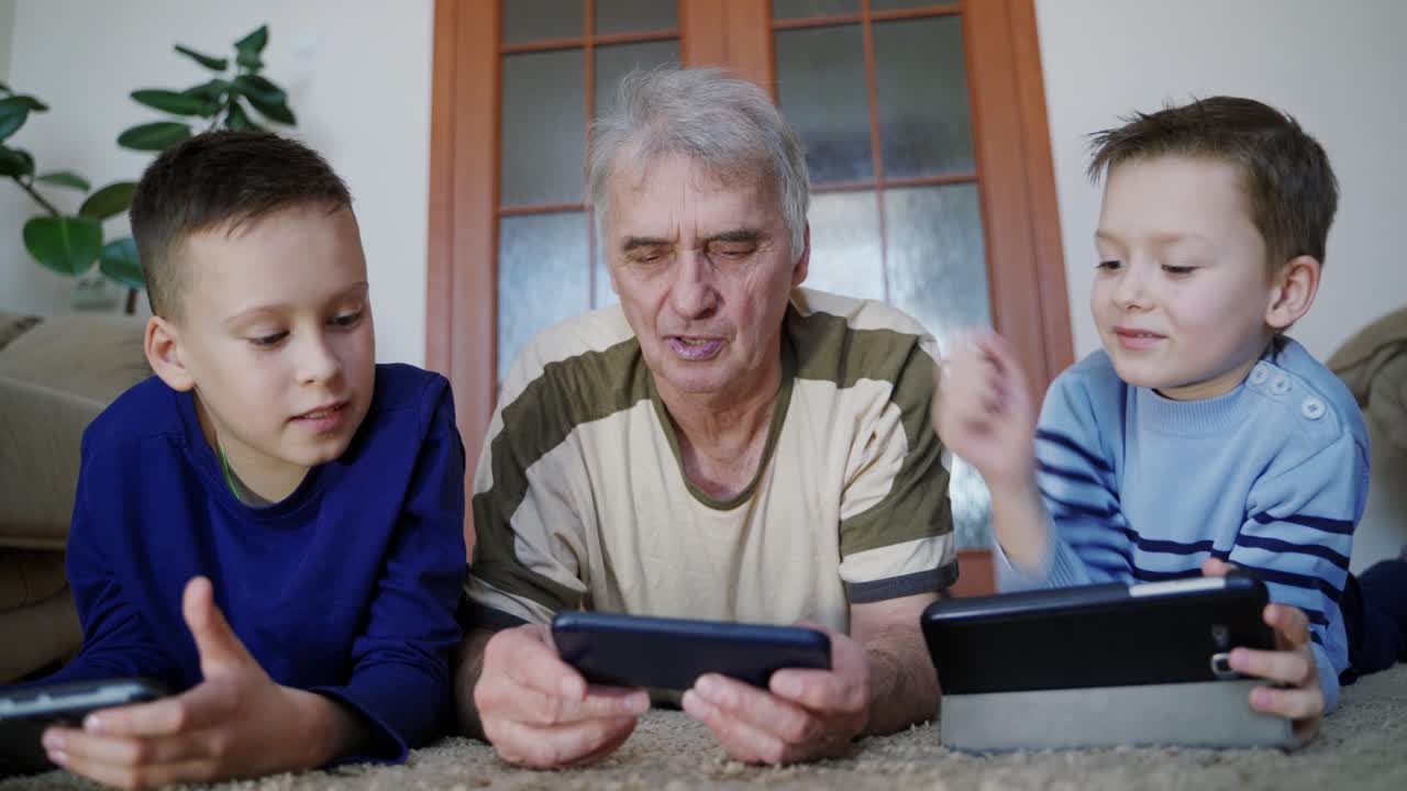 Granddad and grandchildren play on tablet in internet game in room. Home education. Fun pastime.
