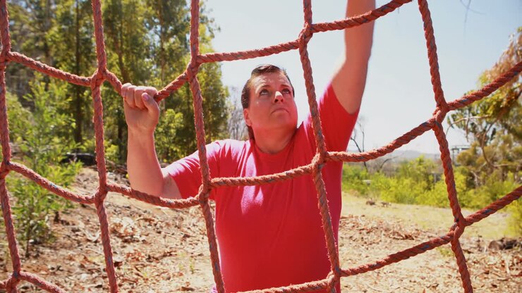 Determined woman climbing a net during obstacle course