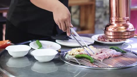 chef grilling meat and vegetables on korean bbq