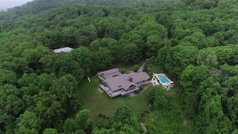 4k aerial orbiting large house in lush green forest with pool, real estate