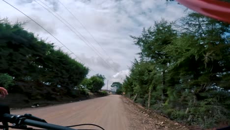 two bicyclists ride their bicycle on a road inside of a forest, hill, and village in guatemala, north america