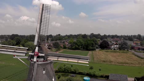 aerial backwards movement showing dutch agriculture countryside in the netherlands revealing the wicks and top of a typical windmill in the landscape