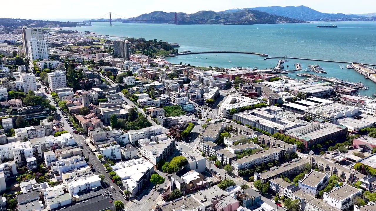 Grabación aérea con dron sobre el distrito de Marina de San Francisco, revelando tejados, la bahía y el Puente Golden Gate a lo lejos