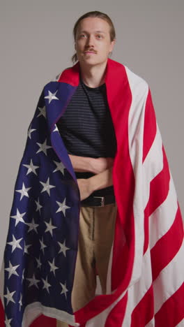 vertical video studio shot of man wrapped in american flag celebrating 4th july independence day 2