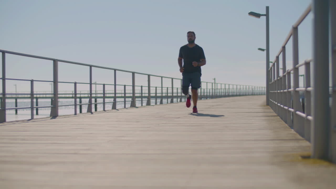 atleta masculino con una pierna artificial corriendo en el puente.