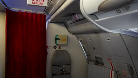 Pan-inside-the-plane-showing-emergency-exit-sign-with-curtains-on-the-plane