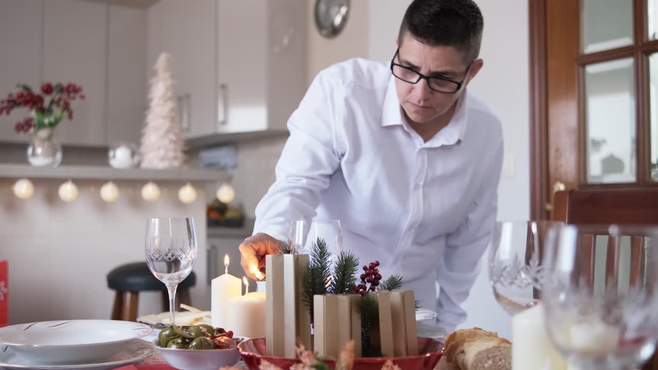 Person lighting the candles on a decorated Christmas table at home