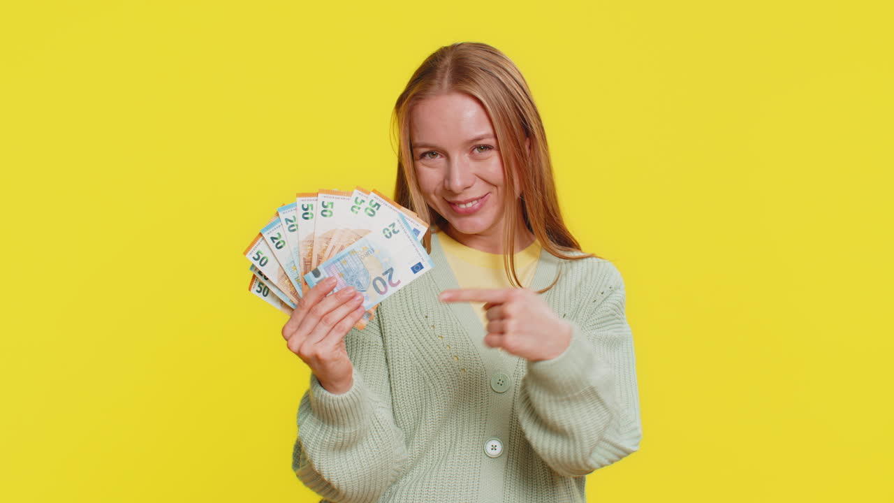 Smiling Woman Showing and Offering Euro Banknotes on Yellow Background