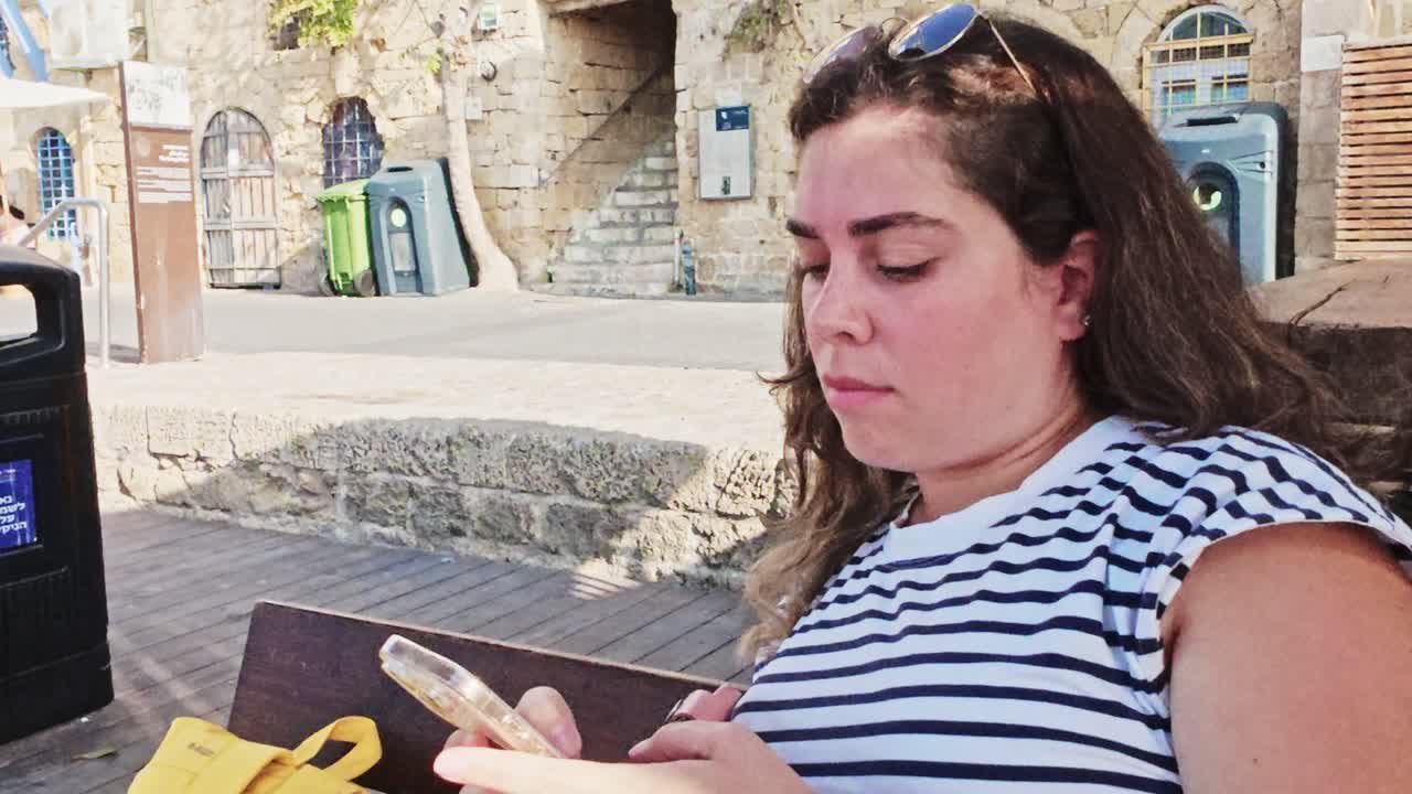 Serious Female Tourist Checking Emails On Phone During Vacation