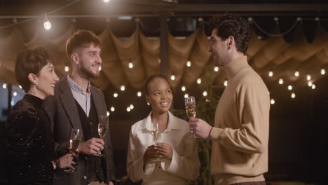 group of four multiethnic friends toasting and drinking champagne at new year's eve party