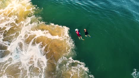 toma aérea de drones de 2 bodyboarders flotando y esperando en el banco de arena ocean break costa central de avoca norte nsw australia 4k