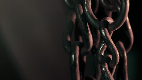 fixed shot, dark rustic chains against dark background