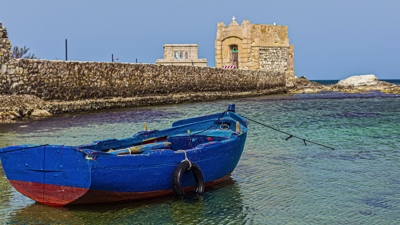 barco de madera con las ruinas de la torre di ligny en el fondo en trapani, sicilia, italia