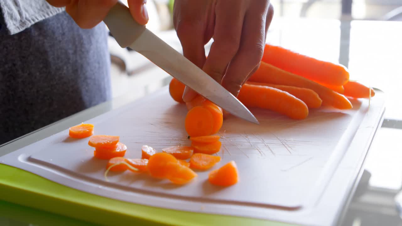 Woman chopping carrot in kitchen at home 4k